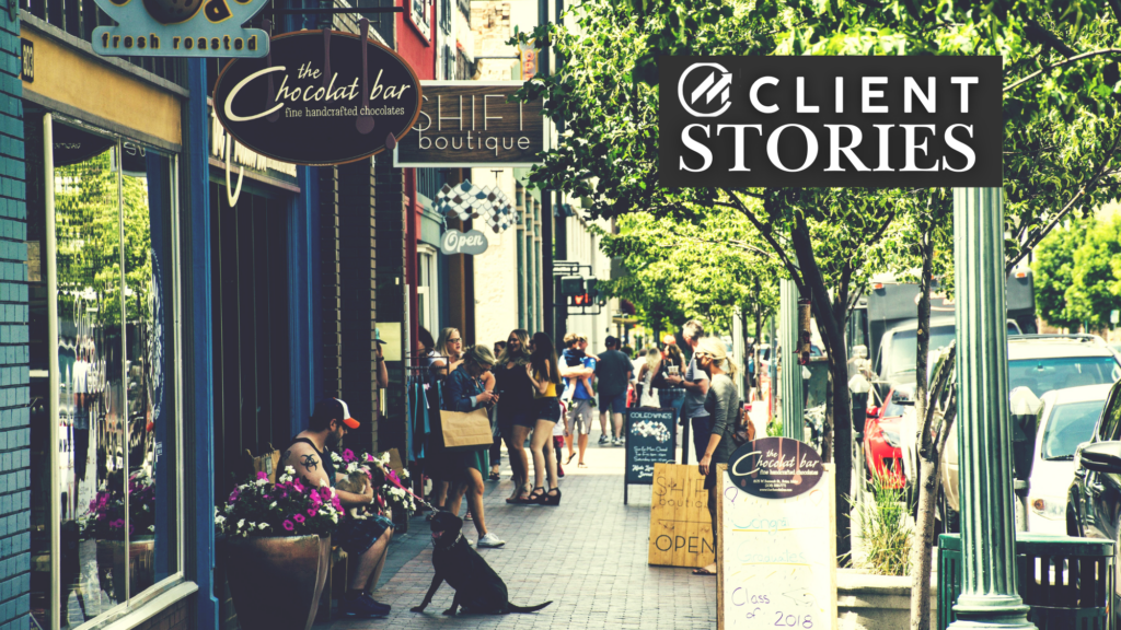 A tree-lined sidewalk next to several shops and businesses.