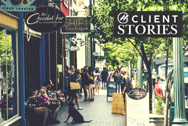 A tree-lined sidewalk next to several shops and businesses.