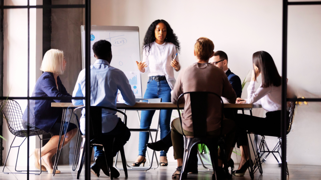 A Sales Funnel Consultant running a small meeting with people sitting around a table.