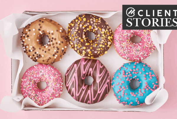 Six tasty-looking frosted donuts in a tissue-lined box.